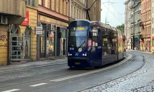 Niebieski tramwaj z napisem "Biskupin" na wyświetlaczu, jadący po brukowanej ulicy w mieście.