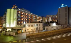 Hotel Don Juan Resort nocą, z neonowym oświetleniem i widokiem na wiele balkonów.