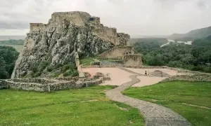Ruiny zamku Devín na skalistym wzgórzu nad Dunajem, z kamienną ścieżką i zielonymi trawnikami.
