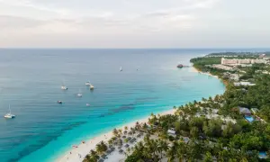 Rajska plaża na Zanzibarze z turkusową wodą, palmami i łodziami. Sprawdź aktualne zanzibar ceny, by zaplanować wymarzone wakacje.