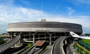 Charakterystyczny Terminal 1 na lotniskach w Paryżu, z krętymi drogami i fragmentem samolotu Qatar Airways.