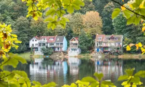 Idealna wycieczka na niedzielę na Dolny Śląsk: domki nad jeziorem w jesiennej scenerii, odbijające się w spokojnej wodzie.