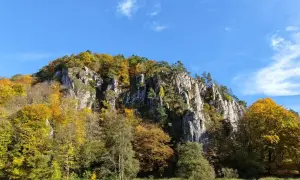 Skały porośnięte jesiennymi drzewami pod błękitnym niebem.