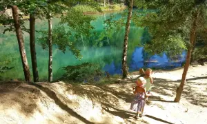 Dwie dziewczynki w słomkowych kapeluszach idą ścieżką nad turkusowe jezioro. Idealne miejsce, gdzie w góry z dziećmi na letnią przygodę.