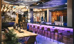 Nowoczesny bar w Moxy Hotels Pyrzowice z neonowym oświetleniem, drewnianym blatem i artystycznymi muralami.