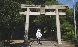 Pielgrzym w tradycyjnym stroju przechodzi pod bramą torii na wyspie Shikoku.