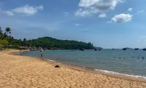 Piękna plaża i turkusowe morze, idealne na wietnam wakacje. W oddali widać łodzie i zieloną wyspę.