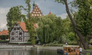 Nietypowe atrakcje Bydgoszcz: malowniczy widok na Brdę z zabytkową architekturą i łodzią.