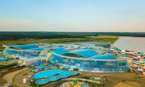 Nowoczesny, największy park wodny w Polsce z błękitnymi dachami i kolorową fasadą, otoczony zielenią.