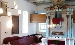 Wnętrze kościoła w Gietrzwałdzie. Ołtarz główny z krzyżem, obrazy, ławy i żyrandol.
