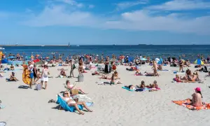 Tłumy ludzi na plaży, opalanie i kąpiel w morzu. Zastanawiasz się, ile kosztuje nocleg nad morzem w sezonie?