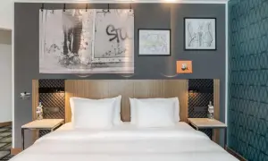 Łóżko w nowoczesnym pokoju hotelowym z białymi pościelami i ozdobami na ścianie.