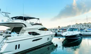Luksusowe jachty cumują w słonecznym Puerto Banús. Błękitne niebo i spokojna woda odbijają białe kadłuby.