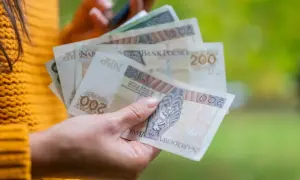 Dłoń trzyma polskie banknoty 200 zł. Zastanawiasz się, ile to netto po przekroczeniu drugiego progu podatkowego?