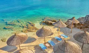 Albania - wczasy samolotem all inclusive. Słoneczna plaża z leżakami i parasolami, turkusowe morze. Idealne miejsce na relaks.