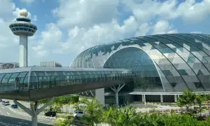 Nowoczesny terminal lotnisko w Singapurze z charakterystyczną szklaną kopułą i wieżą kontroli lotów.