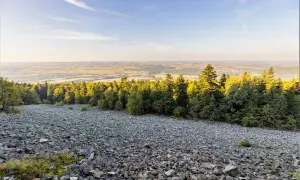 Kamieniste zbocze z gołoborzem, lasem i widokiem na dolinę w Łysogórach.