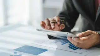 Biznesmen analizuje dane na tablecie, przygotowując się do wnioskowania o pomoc de minimis.