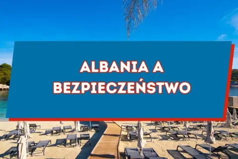Piękna plaża w Albanii, gdzie słońce świeci, a leżaki czekają. Czy w Albanii jest bezpiecznie? Odpowiedź znajdziesz na niebieskim tle.