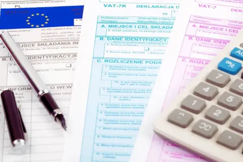 Deklaracja VAT UE, długopis i kalkulator na dokumentach podatkowych.