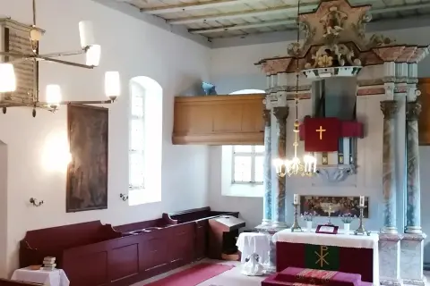 Wnętrze kościoła w Gietrzwałdzie. Ołtarz główny z krzyżem, obrazy, ławy i żyrandol.