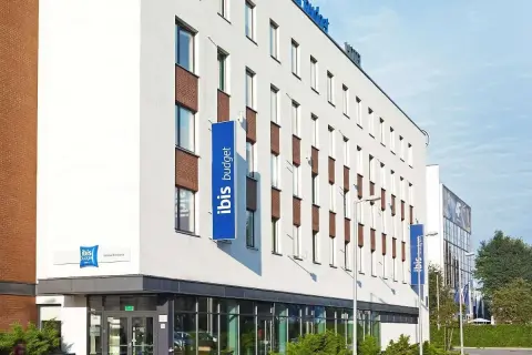 Nowoczesny budynek hotelu ibis budget z niebieskimi banerami.