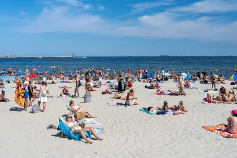 Tłumy ludzi na plaży, opalanie i kąpiel w morzu. Zastanawiasz się, ile kosztuje nocleg nad morzem w sezonie?