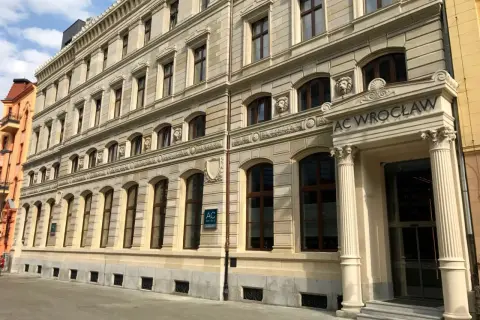 Elegancki budynek AC Hotel Wrocław z kamienną fasadą i ozdobnymi detalami.