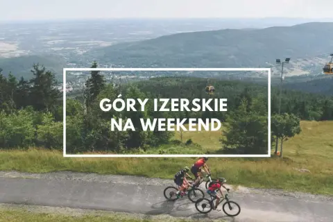 Góry Izerskie Polska: rowerzyści pędzą po górskiej drodze, a w tle kolejka gondolowa i rozległy krajobraz.