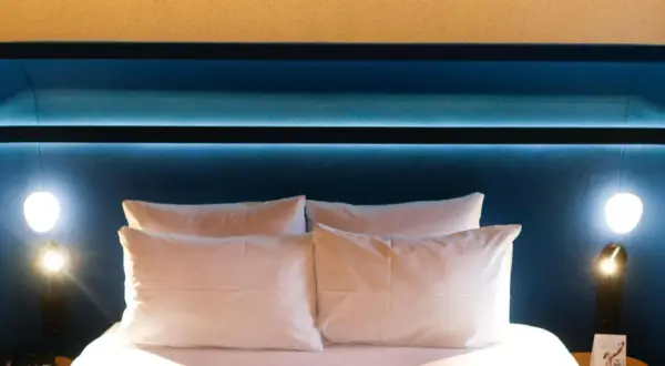 Komfortowe łóżko z białymi poduszkami w pokoju hotelowym Mercure Warszawa Centrum.