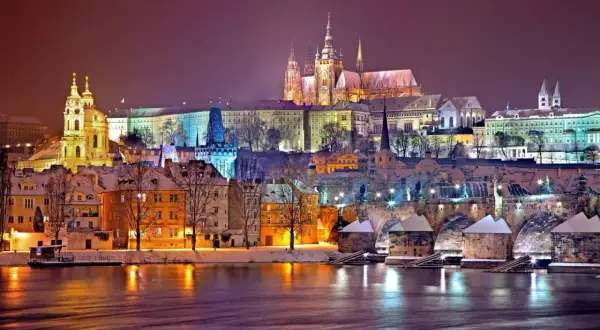 Wieczorny widok na Pragę zimą. Zamek na wzgórzu, most Karola i kolorowe kamienice tworzą magiczny krajobraz. Ciekawe ciekawostki o Czechach czekają na odkrycie!
