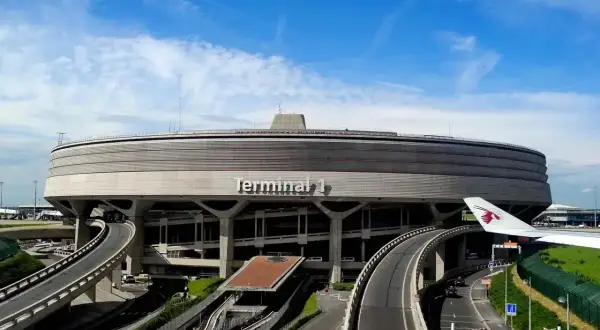 Charakterystyczny Terminal 1 na lotniskach w Paryżu, z krętymi drogami i fragmentem samolotu Qatar Airways.