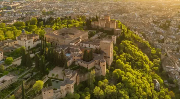 Widok z lotu ptaka na Alhambrę w Granadzie, otoczoną bujną zielenią. Marzysz o zwiedzaniu? Sprawdź alhambra bilety!