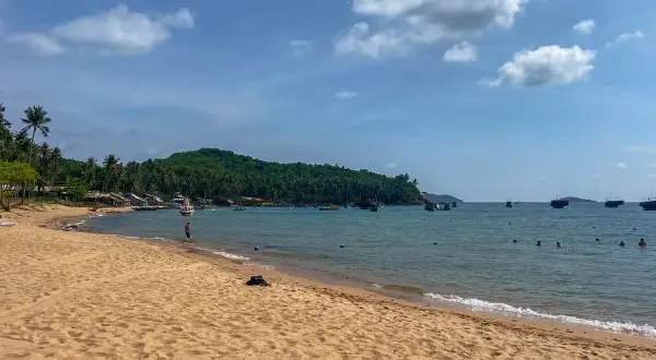 Piękna plaża i turkusowe morze, idealne na wietnam wakacje. W oddali widać łodzie i zieloną wyspę.