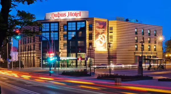 Hotel Qubus Gorzów nocą, z widocznymi światłami samochodów na ulicy i neonem hotelu.