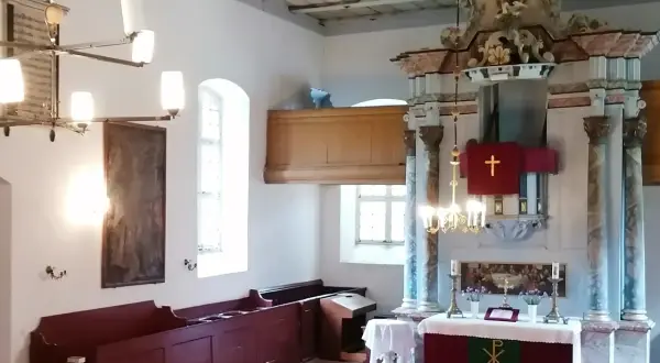 Wnętrze kościoła w Gietrzwałdzie. Ołtarz główny z krzyżem, obrazy, ławy i żyrandol.
