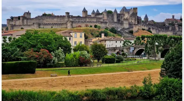 Majestatyczna twierdza Carcassonne góruje nad miastem, otoczona zielenią i rzeką.