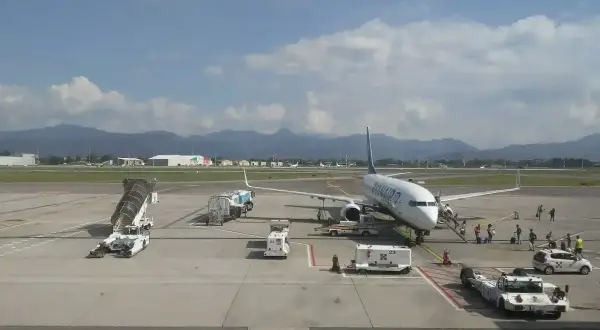Samolot Ryanair na płycie lotniska Bergamo. W tle góry i budynki lotniskowe.