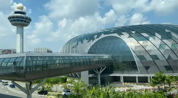 Nowoczesny terminal lotnisko w Singapurze z charakterystyczną szklaną kopułą i wieżą kontroli lotów.