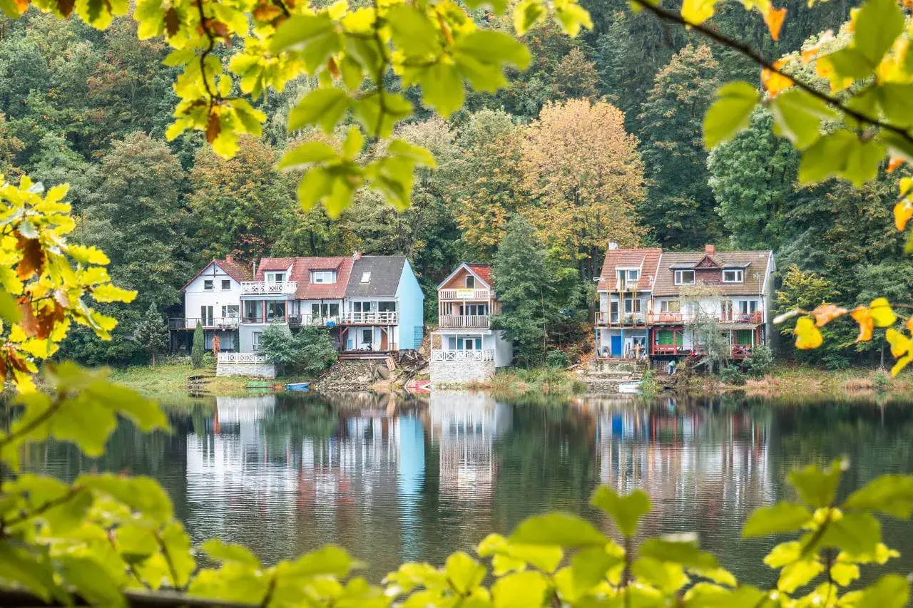 Idealna wycieczka na niedzielę na Dolny Śląsk: domki nad jeziorem w jesiennej scenerii, odbijające się w spokojnej wodzie.