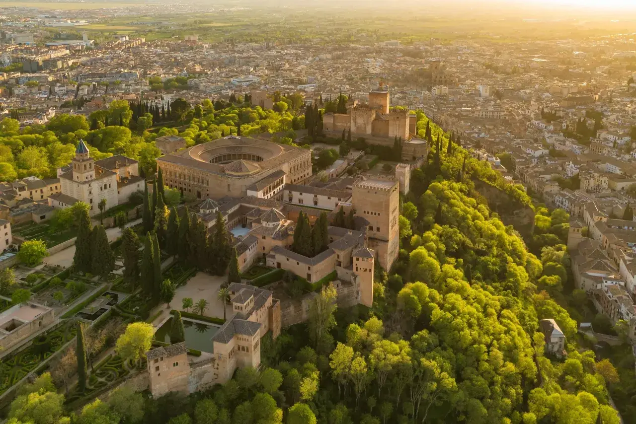 Widok z lotu ptaka na Alhambrę w Granadzie, otoczoną bujną zielenią. Marzysz o zwiedzaniu? Sprawdź alhambra bilety!