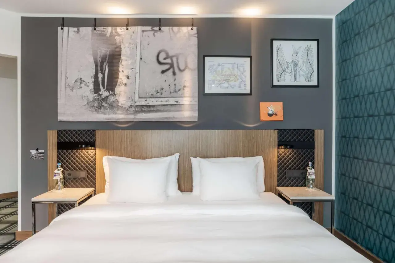 Łóżko w nowoczesnym pokoju hotelowym z białymi pościelami i ozdobami na ścianie.