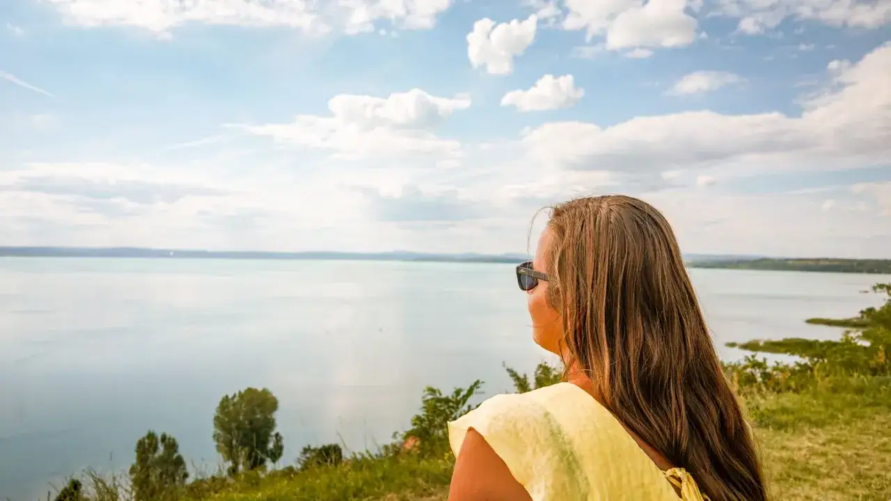Kobieta w okularach przeciwsłonecznych podziwia rozległe jezioro Balaton.
