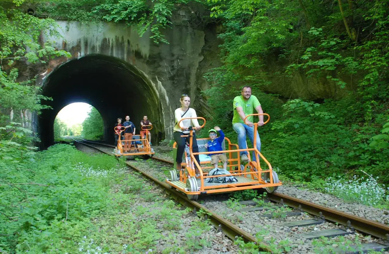 Rodzina na drezynach w Bieszczadach, przejeżdża przez zielony tunel.
