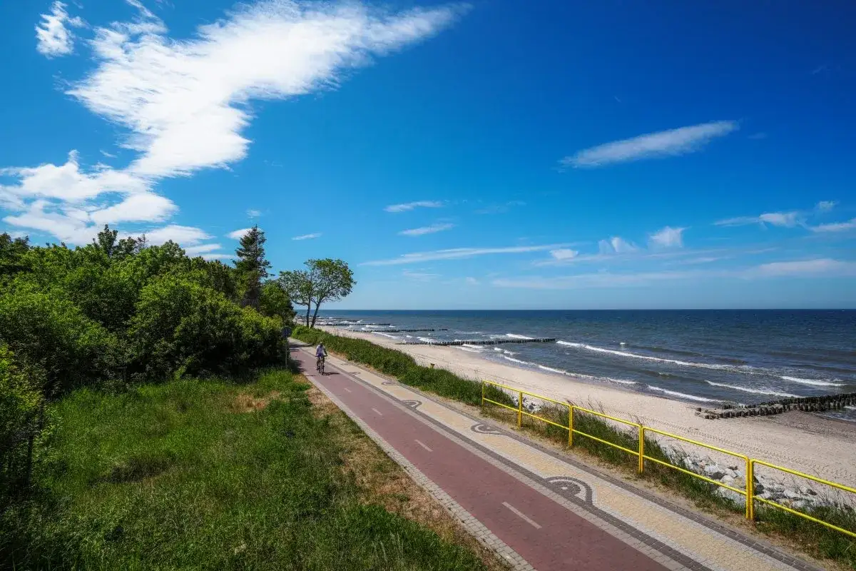 Piękna ścieżka rowerowa wzdłuż plaży, idealna do odkrywania urokliwych miejscowości nad morzem.