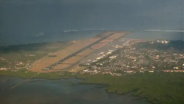 Widok z lotu ptaka na lotnisko na Bali, z pasem startowym biegnącym wzdłuż wybrzeża i miastem w tle.