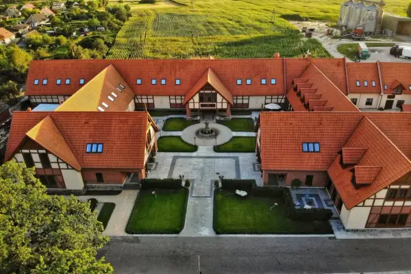 Urokliwy dworek z czerwonym dachem, otoczony zielenią i polami kukurydzy. Prawdziwe magiczne miejsca kujawsko-pomorskie.