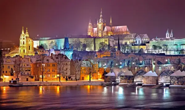 Wieczorny widok na Pragę zimą. Zamek na wzgórzu, most Karola i kolorowe kamienice tworzą magiczny krajobraz. Ciekawe ciekawostki o Czechach czekają na odkrycie!