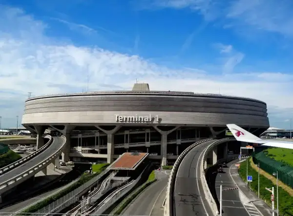 Charakterystyczny Terminal 1 na lotniskach w Paryżu, z krętymi drogami i fragmentem samolotu Qatar Airways.