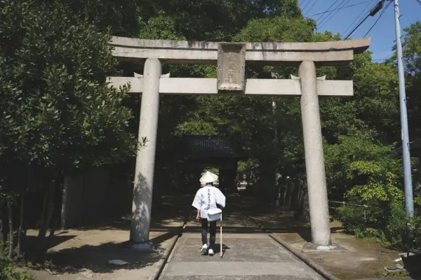 Pielgrzym w tradycyjnym stroju przechodzi pod bramą torii na wyspie Shikoku.